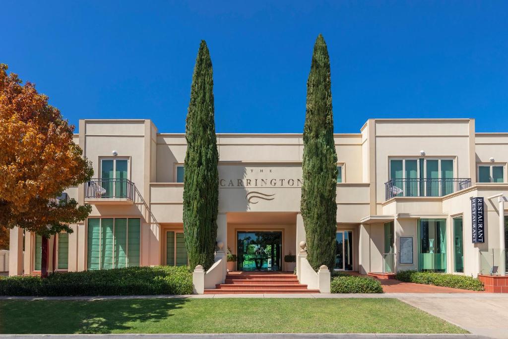 un bâtiment avec deux grands arbres devant lui dans l'établissement The Carrington Hotel, à Shepparton