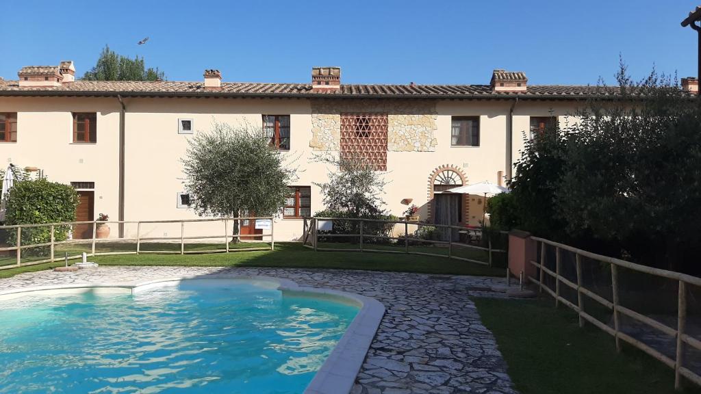 une grande maison avec une piscine en face de celle-ci dans l'établissement Appartamento con piscina Il Borghetto - vicino San Gimignano, à Gambassi Terme