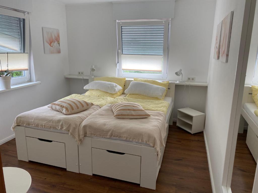 um quarto branco com uma cama com duas almofadas em Haus Sonnenweg 6 auf der Sonnenseite im Westerwald em Höhr-Grenzhausen