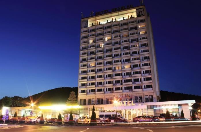 ein hohes Gebäude mit davor geparkt in der Unterkunft GRAND HOTEL CEAHLAU in Piatra Neamţ