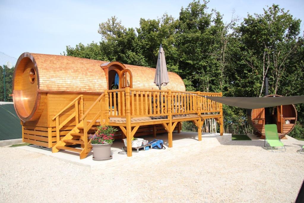 a large wooden house with a deck and an umbrella at L'Insolite Jurassienne in Dompierre-sur-Mont