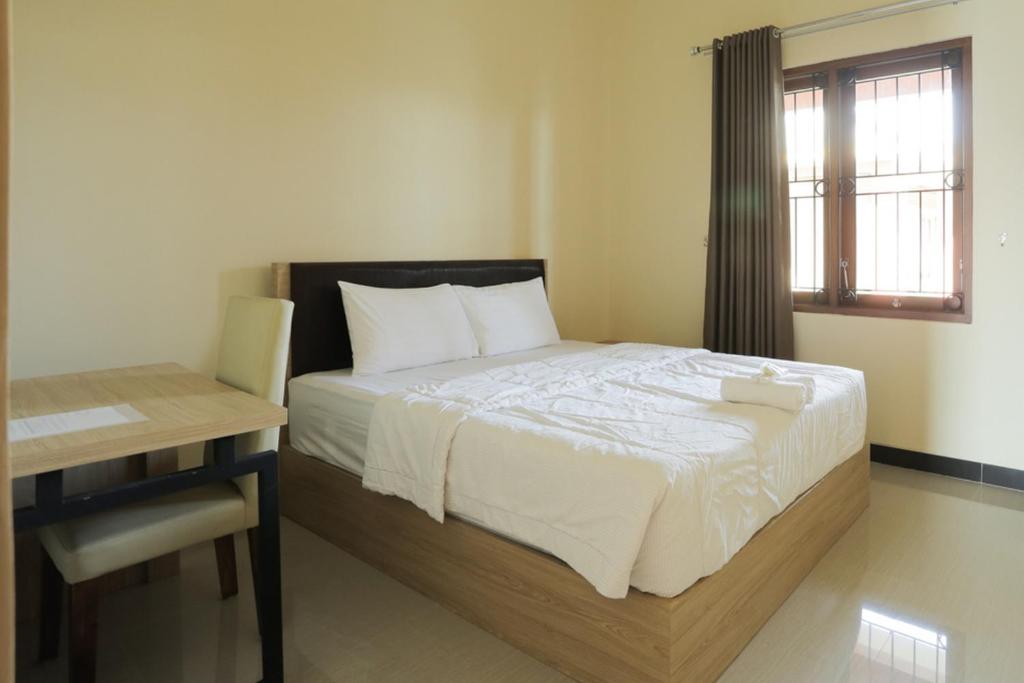1 dormitorio con cama, escritorio y ventana en IDR Green Guest House Syariah Mitra RedDoorz, en Solo