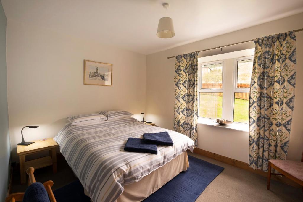 1 dormitorio con cama y ventana en Martinshouse Holiday Cottage, en Hawick