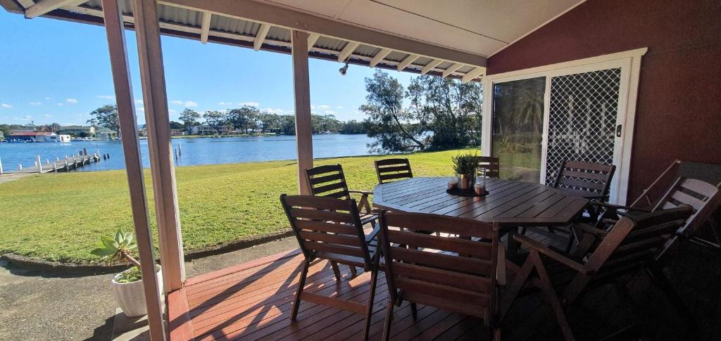 una mesa y sillas en un porche con vistas al agua en Riverfront Cottage in Booderee National Park at Christians Minde, en Jervis Bay Village