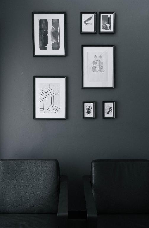 Two dark lounge chairs sit beneath a curated arrangement of framed art.