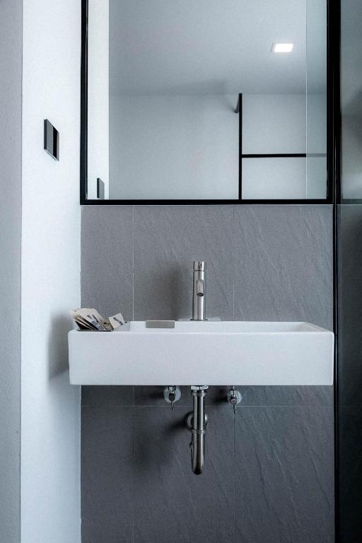 A minimalist wall-mounted bathroom sink beneath a large framed mirror.