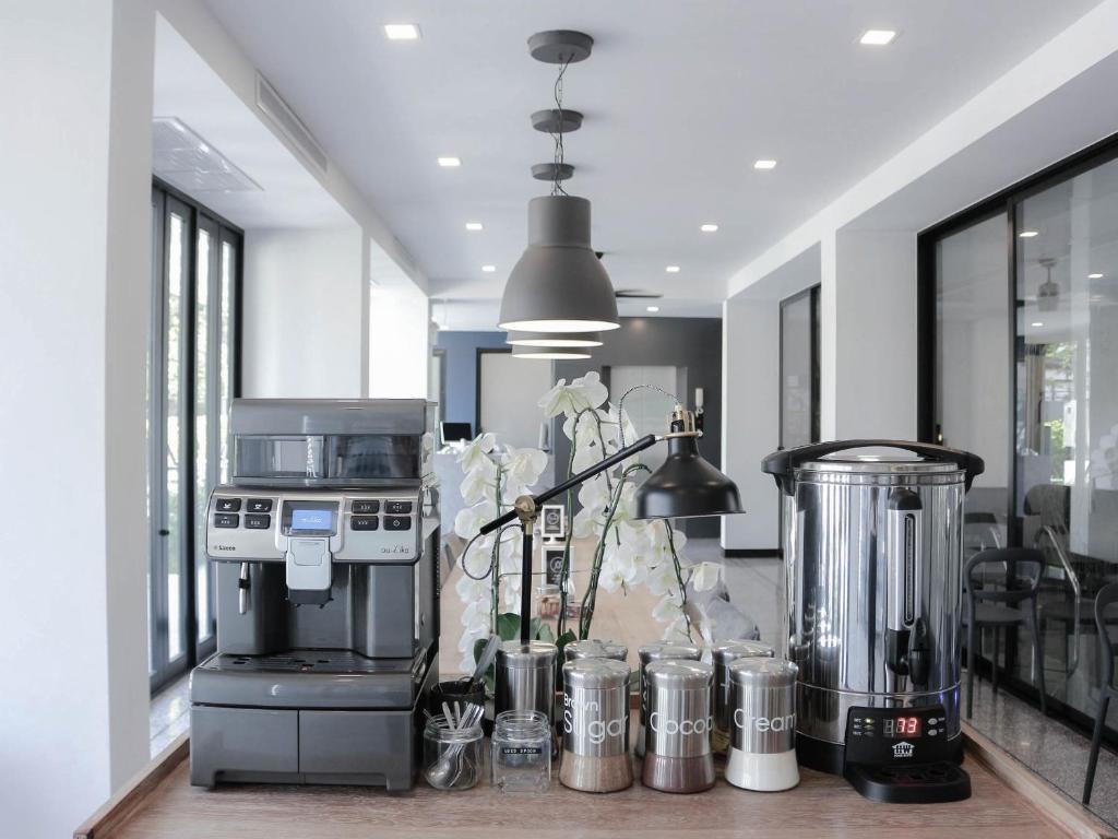 A bright beverage station with a coffee machine, blender, hot-water urn and labeled condiments.
