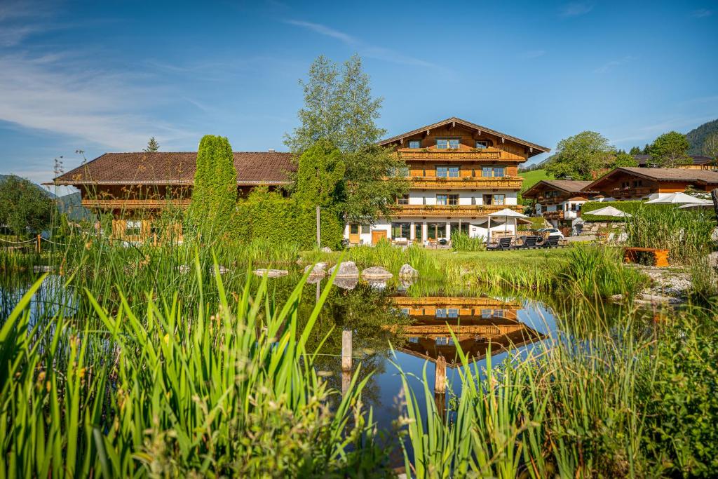 un grande edificio in legno accanto a un corpo d'acqua di Hotel Frohnatur a Thiersee