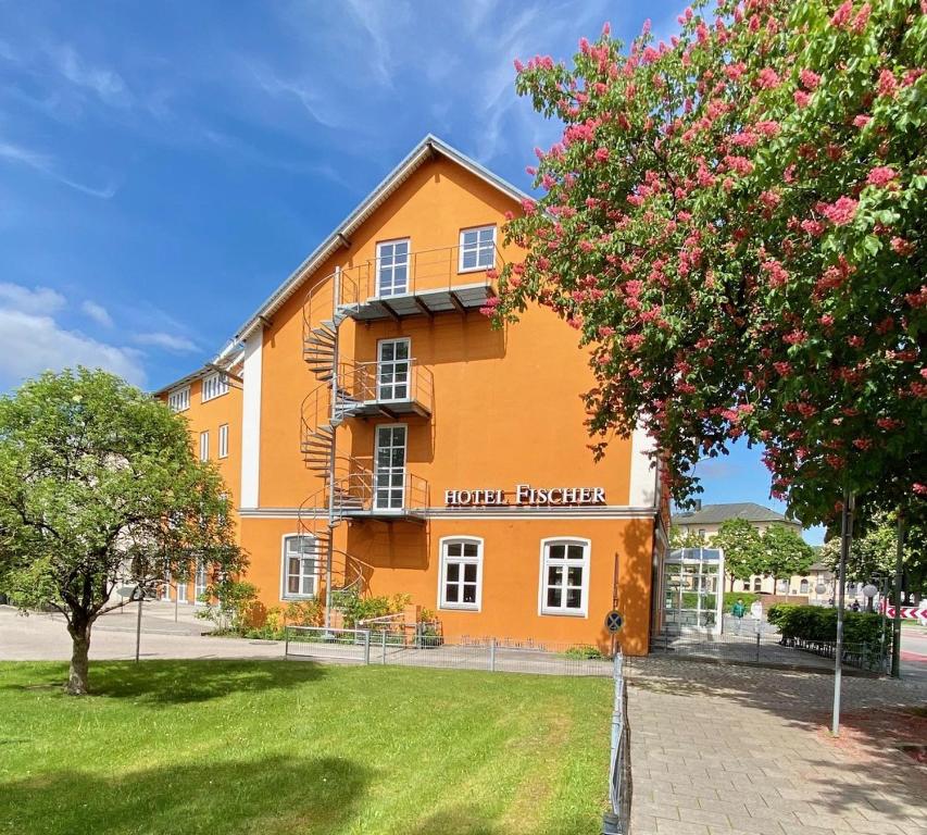 ダッハウにあるHotel zum Fischerの目の前に木が植えられた大きなオレンジ色の建物