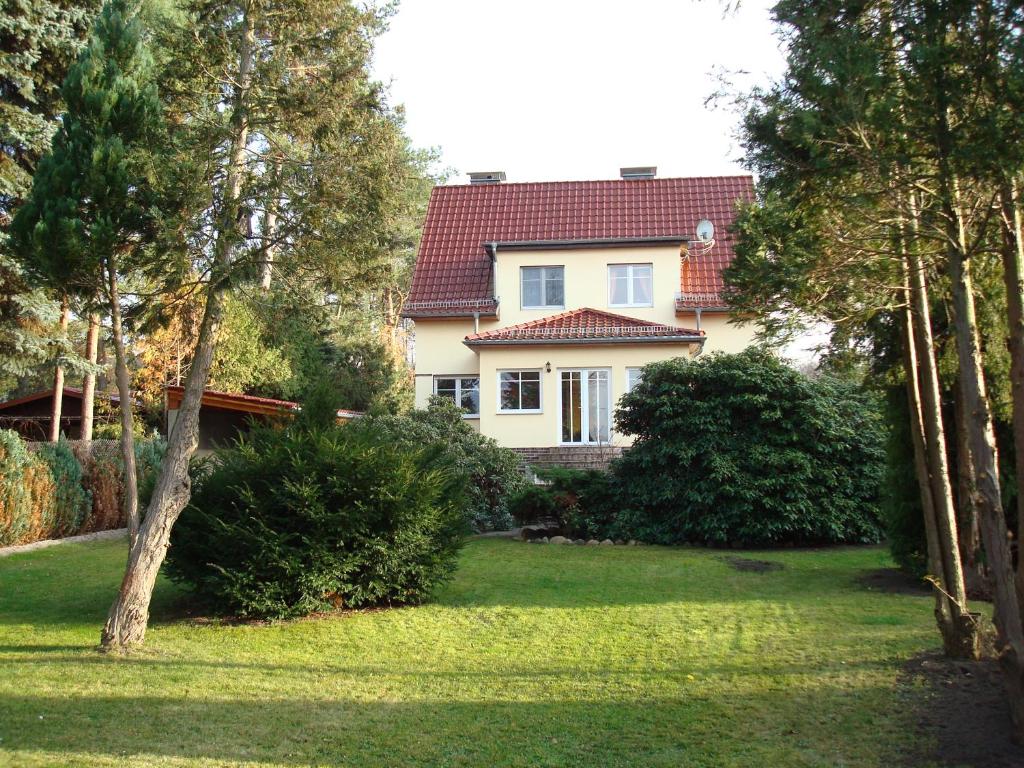 a white house with a red roof in a yard at Haus am Zemminsee in Groß Köris
