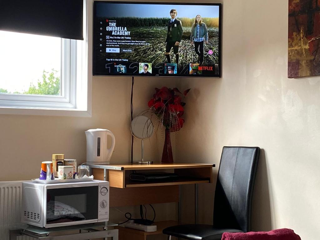 einen an der Wand hängenden TV mit einer Mikrowelle in der Unterkunft Quiet, spacious double bedroom! in Peterborough