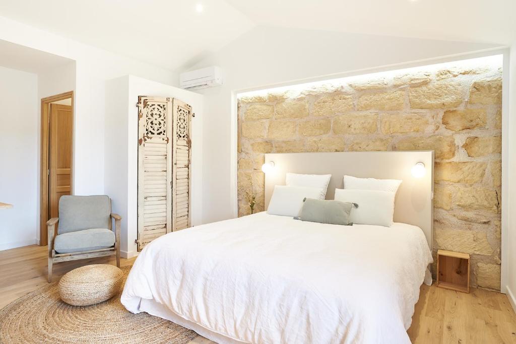 um quarto com uma cama branca e uma parede de pedra em Maison 1634 - Centre historique, parking, petit-dejeuner compris, climatisation, piscine em Pézenas