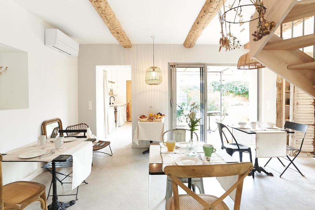een eetkamer met witte tafels en stoelen bij Maison 1634 - petit-déjeuner offert, parking, centre ville à pied, piscine, climatisation, cuisine in Pézenas