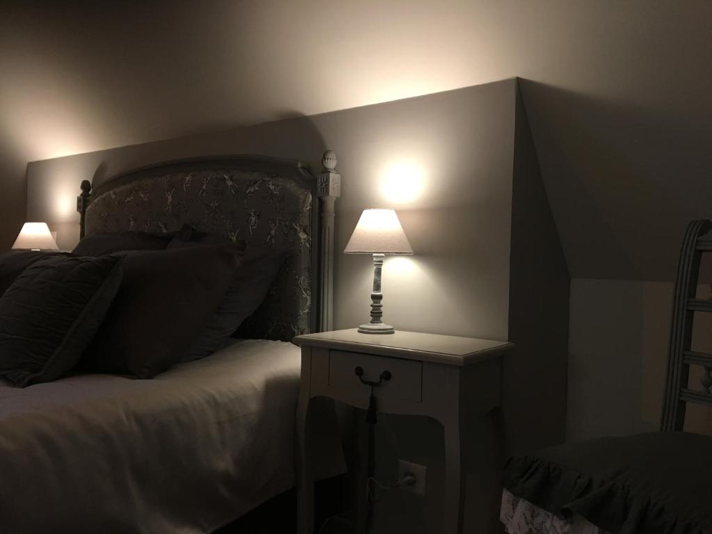 ein Schlafzimmer mit einem Bett und einer Lampe auf einem Nachttisch in der Unterkunft Au gré des saisons in Héricourt