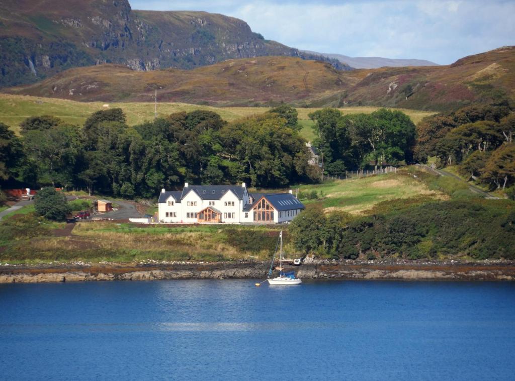 a large house on the shore of a body of water at Redwood House in Greshornish