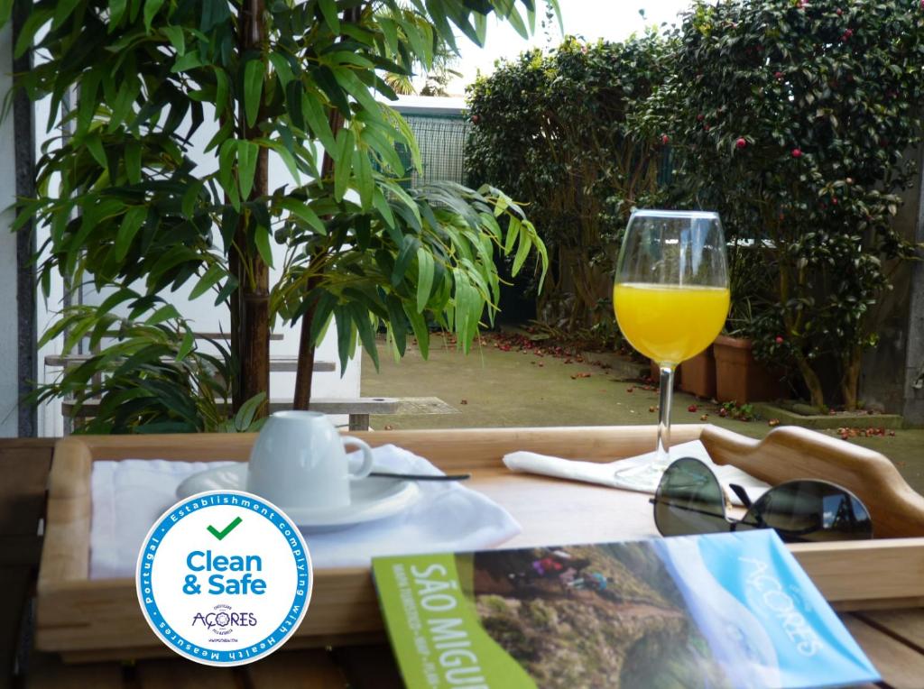 a table with a glass of orange juice and a book at AZORES HOLIDAYS HOUSE -B&B - Suites - Self Check-in KEYBOARD in Ponta Delgada