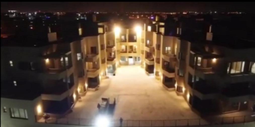 een luchtzicht op een straat 's nachts met gebouwen bij Ras Alkhyran Resort عائلات فقط in An Nāmī