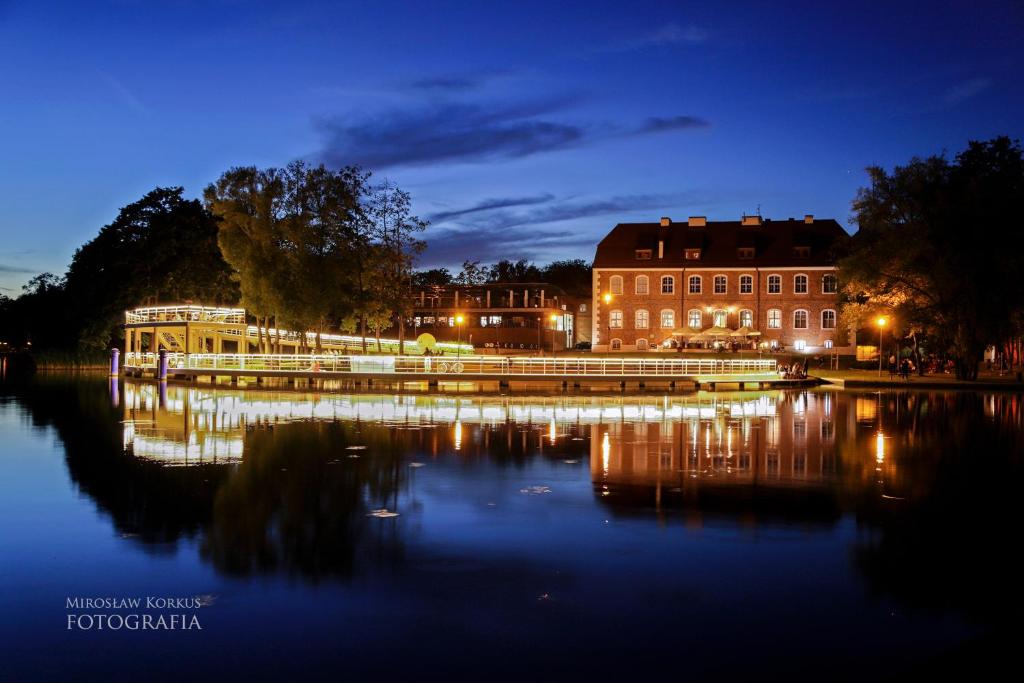una ciudad por la noche con un río y edificios en Centrum Konferencyjne Zamek, en Szczecinek
