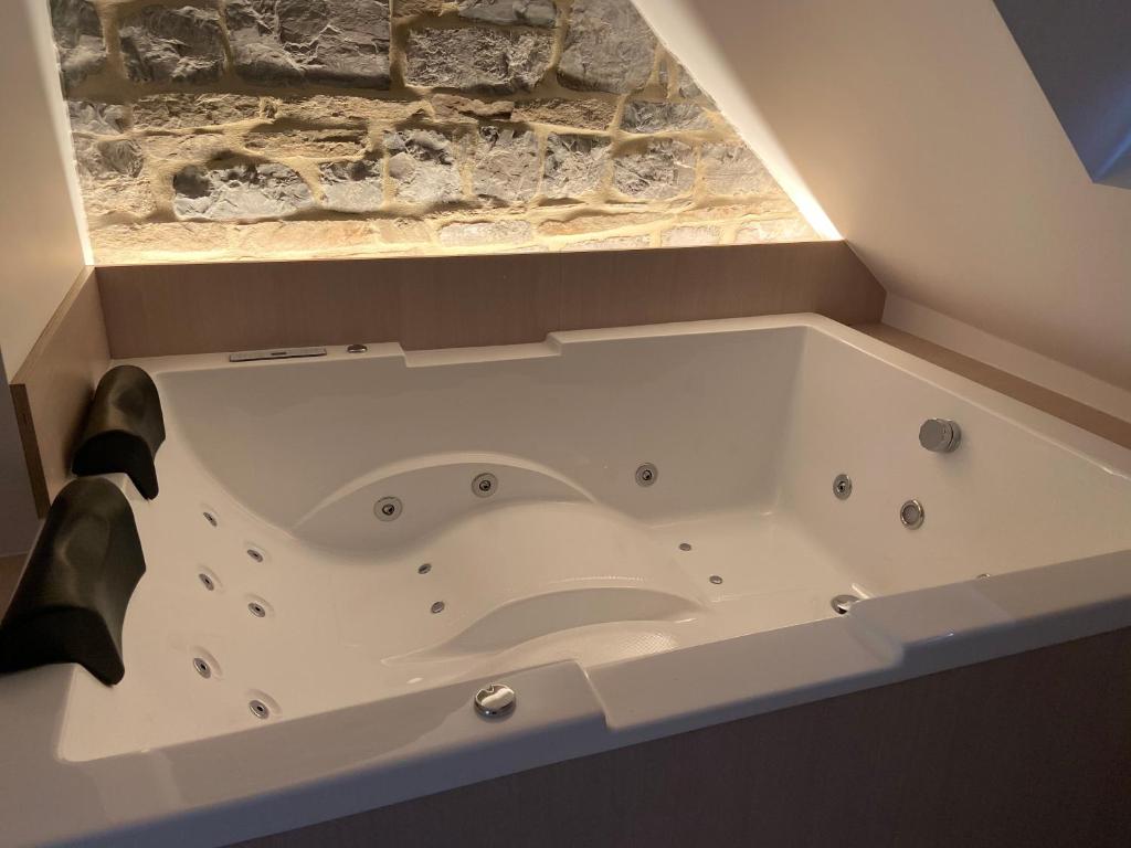 a bath tub in a bathroom with a stone wall at Fenêtre sur Theux in Theux