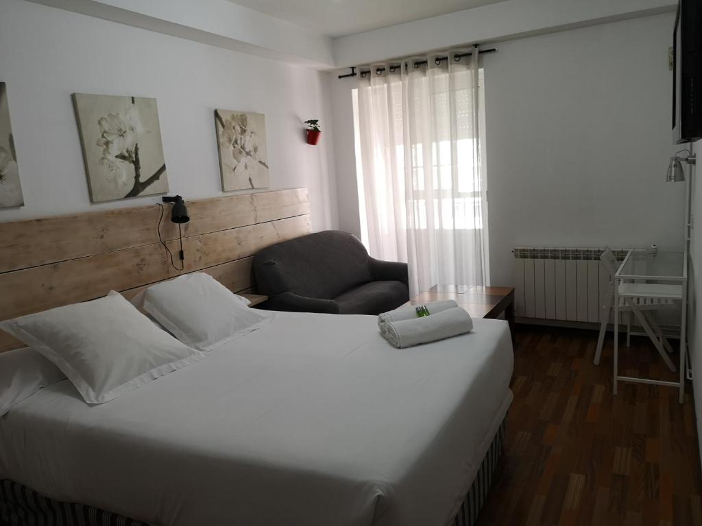 1 dormitorio con 1 cama blanca grande y 1 silla en Hostal Carbonara, en A Coruña