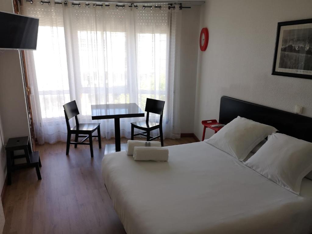 a room with a bed, chair, table and a lamp at Pensión Las Rías in A Coruña