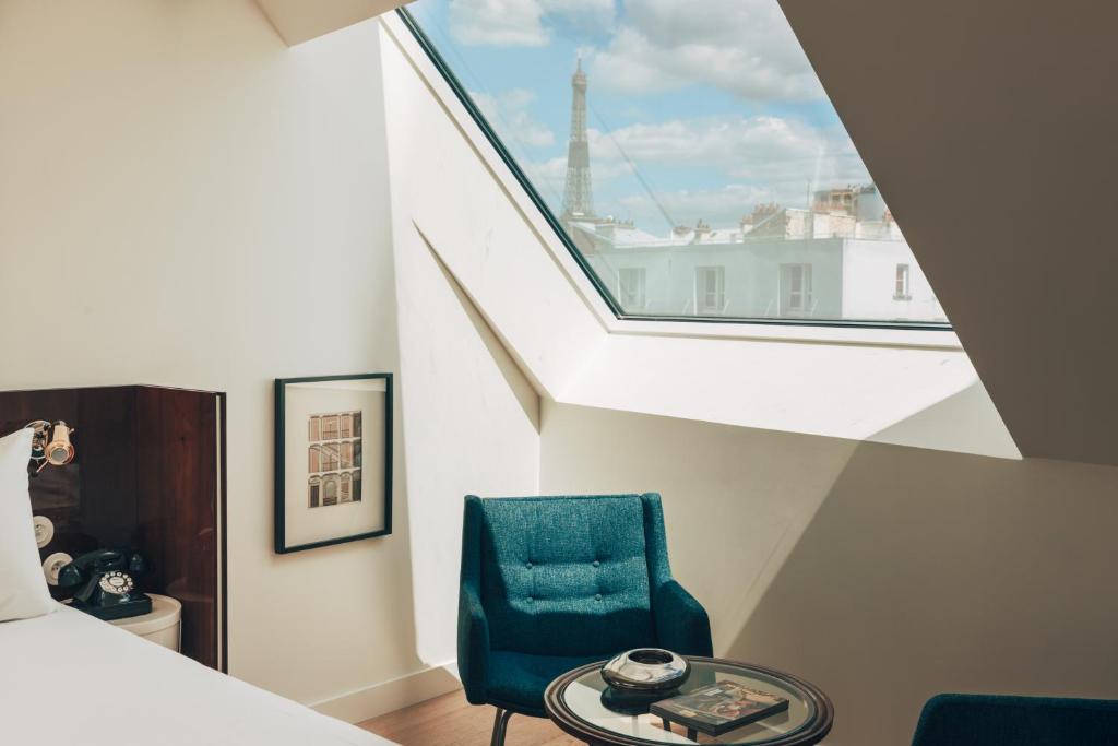 um quarto com uma cadeira azul e uma janela em Hôtel Wallace - Orso Hotels em Paris