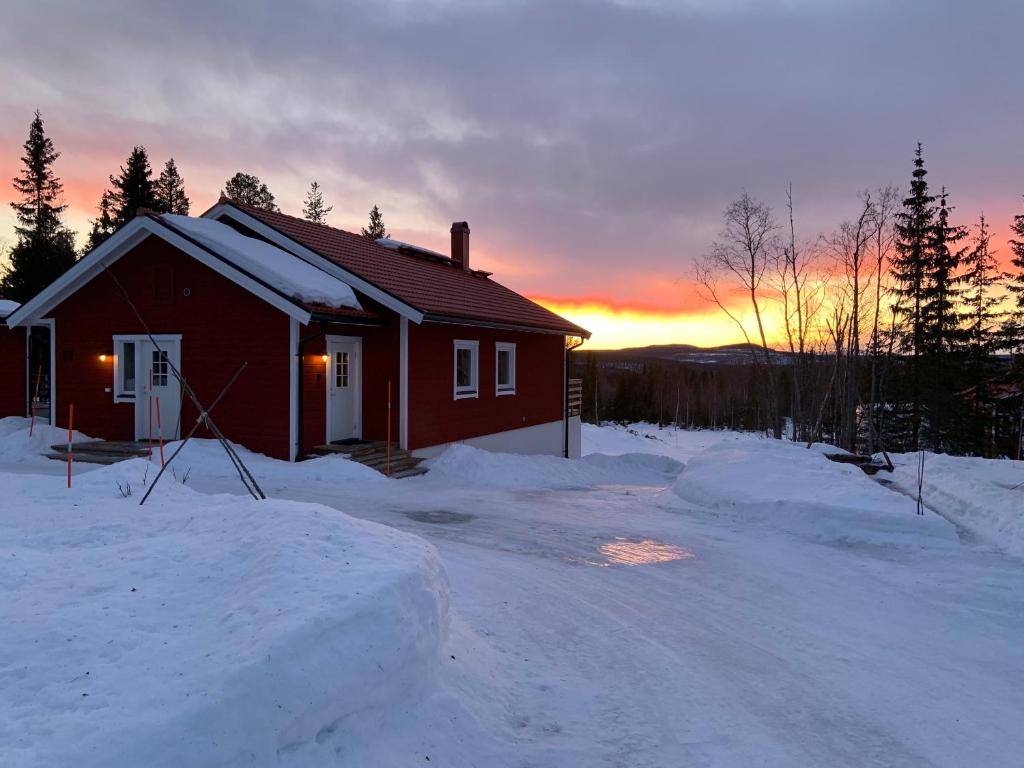 uma casa na neve com o pôr-do-sol ao fundo em Fjällhus 1 em Höstsätern