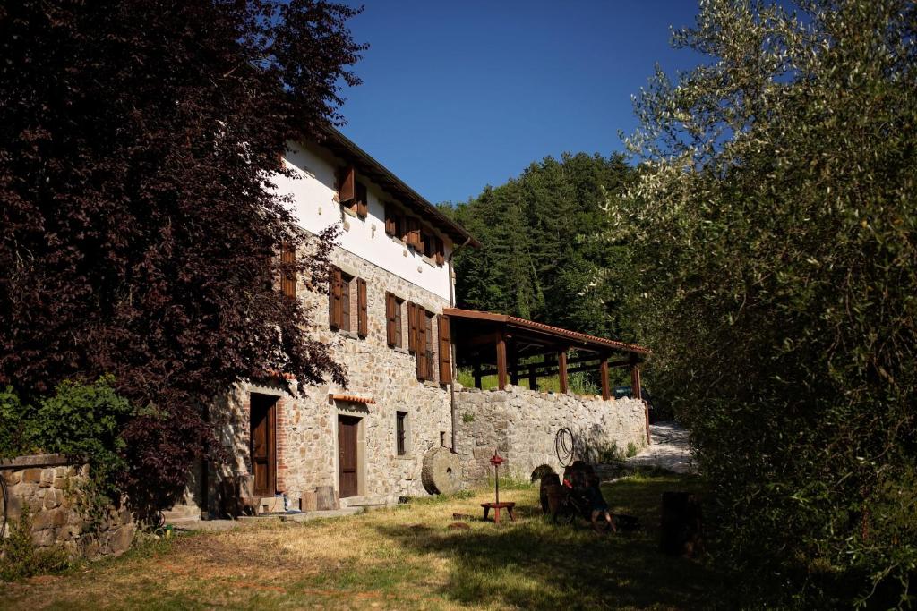 un antiguo edificio de piedra con árboles y un edificio en MULINO VECCHIO, en Minucciano