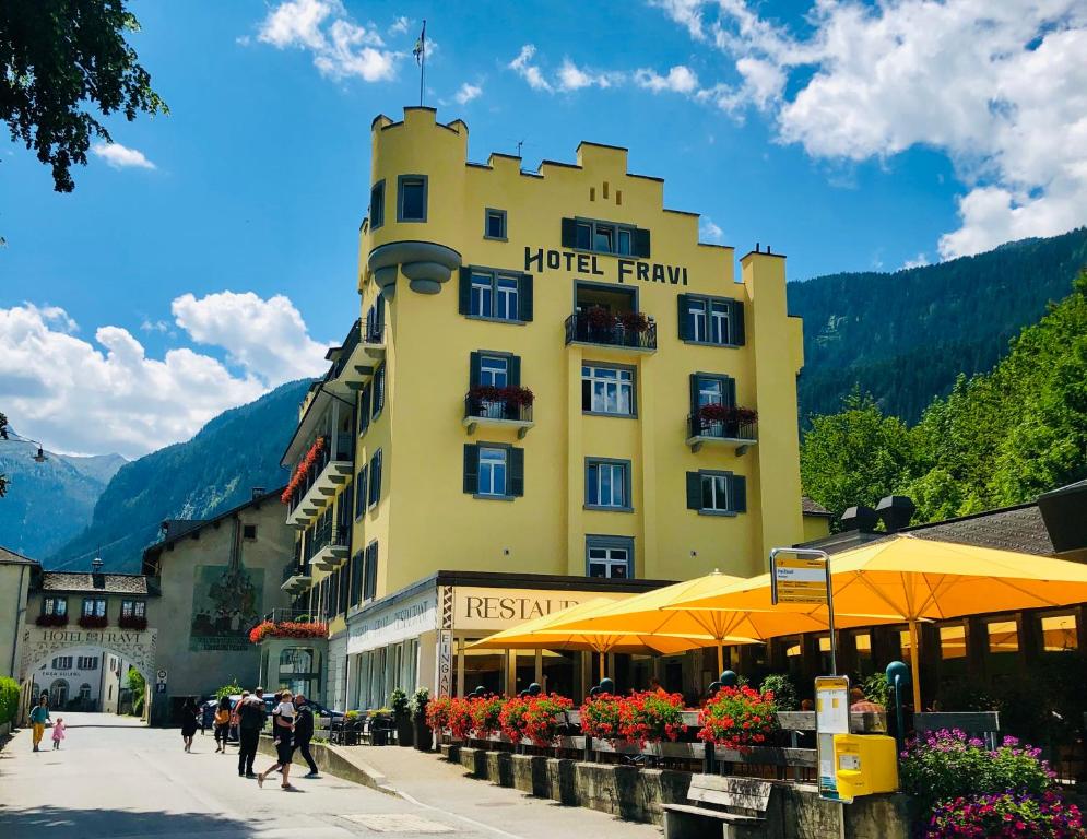 um edifício amarelo com pessoas a andar em frente dele em Hotel Fravi em Andeer