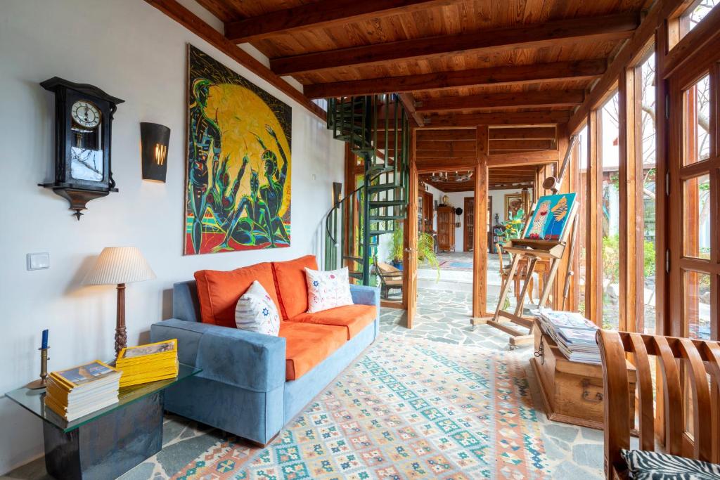 a living room with an orange couch and a clock at Villa El Inti in Tinajo