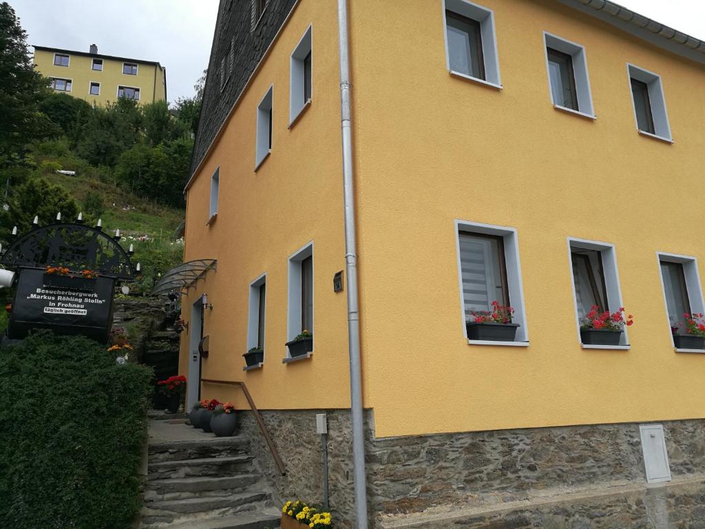 un bâtiment jaune avec des boîtes de fleurs sur les fenêtres dans l'établissement Ferienwohnung zum Bergmann, à Annaberg-Buchholz
