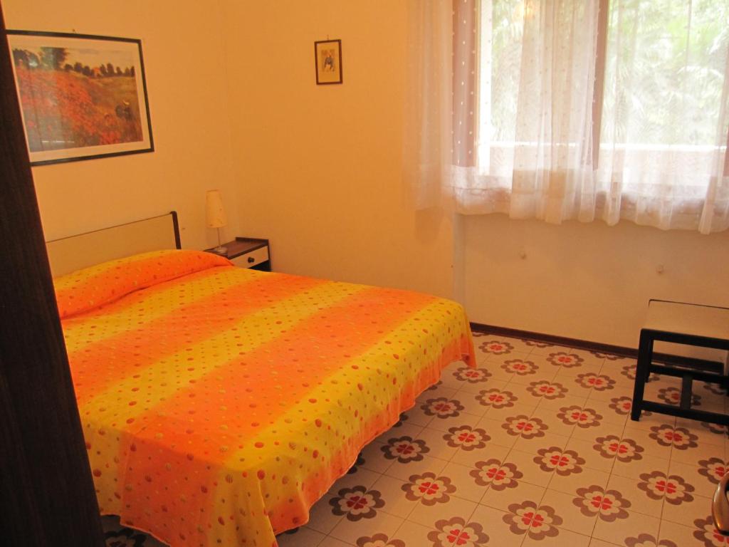 グラードにあるAppartamento Claudiaのベッドルーム1室(オレンジ色の掛け布団付きのベッド1台付)