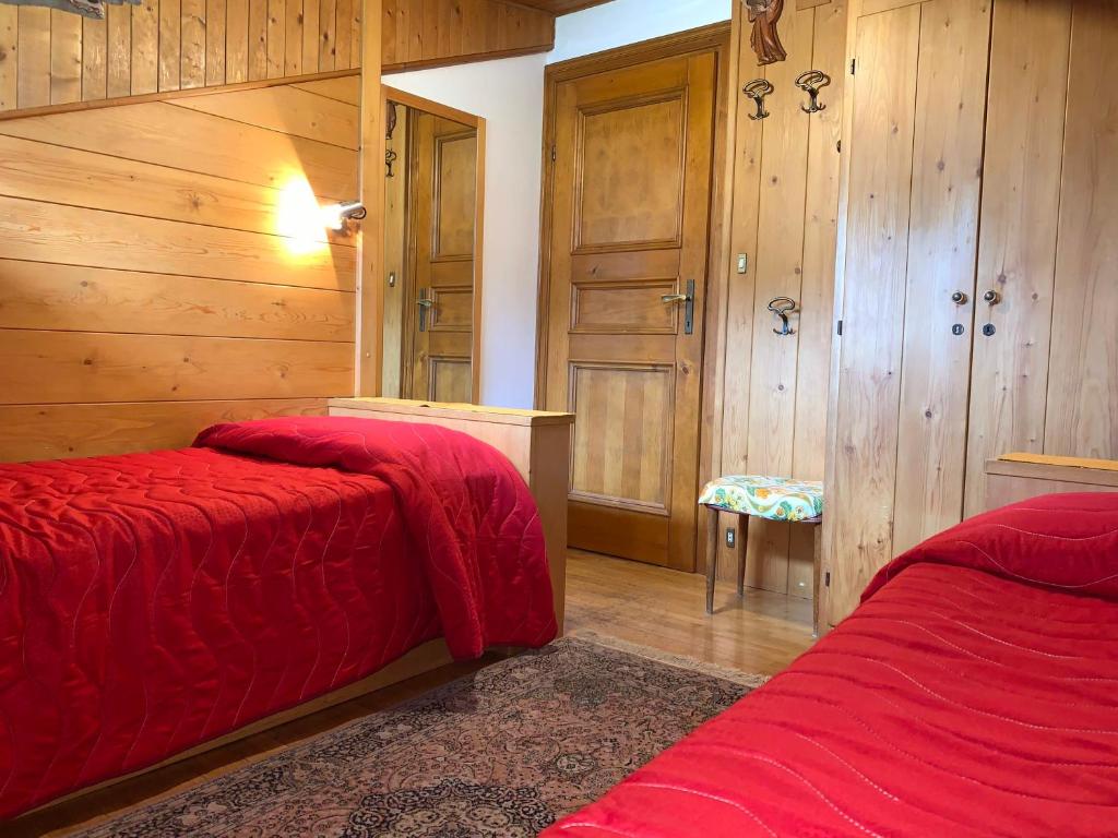 2 letti in una camera con pareti in legno e pavimenti in parquet di Attico Vista Tofane a Cortina dʼAmpezzo