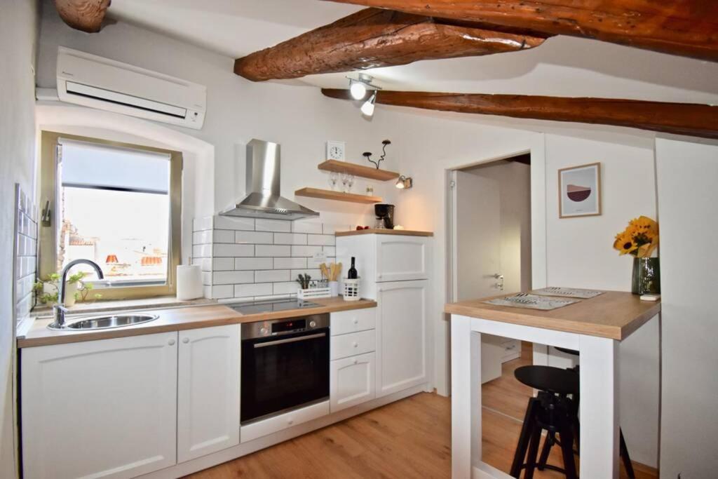 a kitchen with white cabinets and a black dishwasher at Brand New Top Centre Apartment in Pula