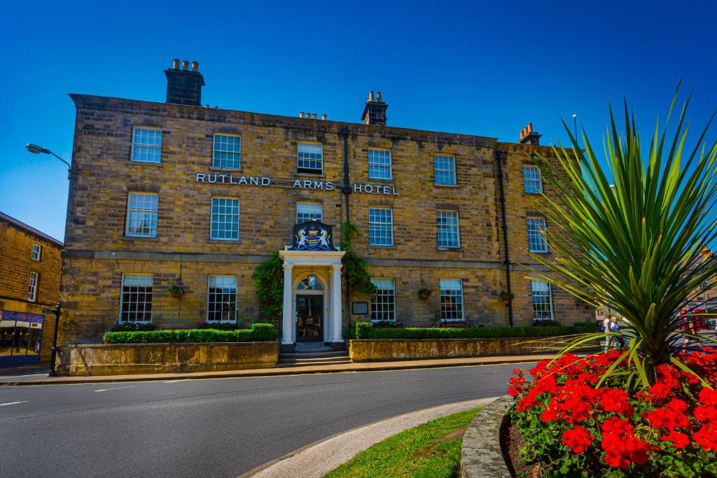 a large brick building with a clock on the front of it at The Rutland Arms Hotel, Bakewell, Derbyshire in Bakewell