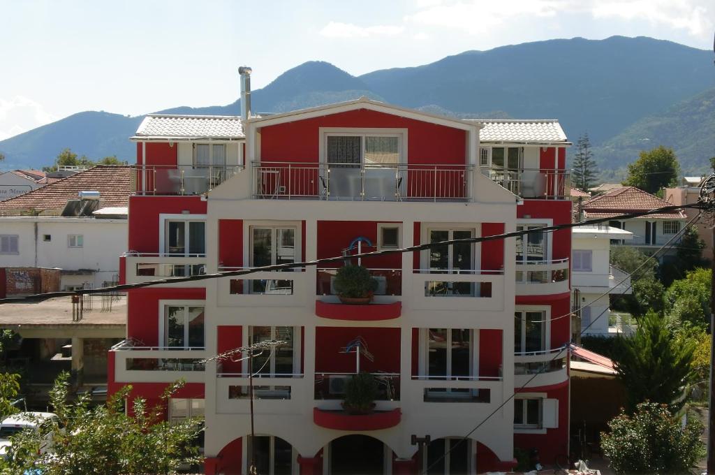 a red and white building with mountains in the background at Valena Studios in Nydri