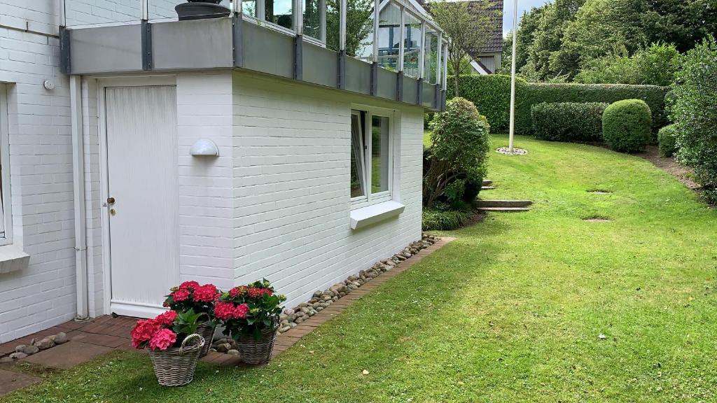 Una casa con dos cestas de flores a un lado. en Ferienwohnung in weißer Villa am Kliff, en Flensburg