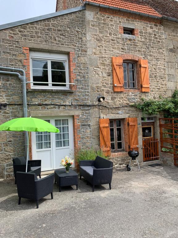 a group of chairs and an umbrella in front of a building at Doxie Cottage in Saint-Chabrais