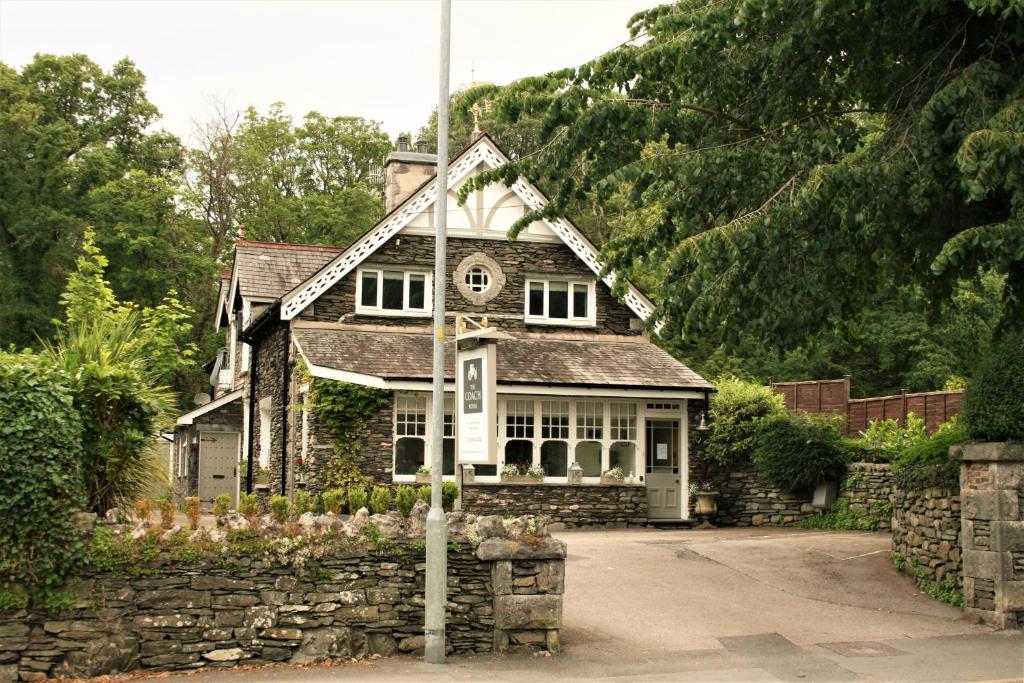 una vieja casa de piedra con una bandera delante de ella en The Coach House, en Windermere