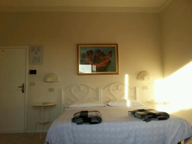a bedroom with a white bed and a picture on the wall at Hotel Signorini in Castiglioncello