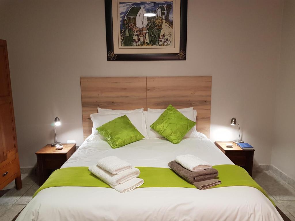 a bedroom with a large white bed with green pillows at Huis van Seisoene in Klerksdorp