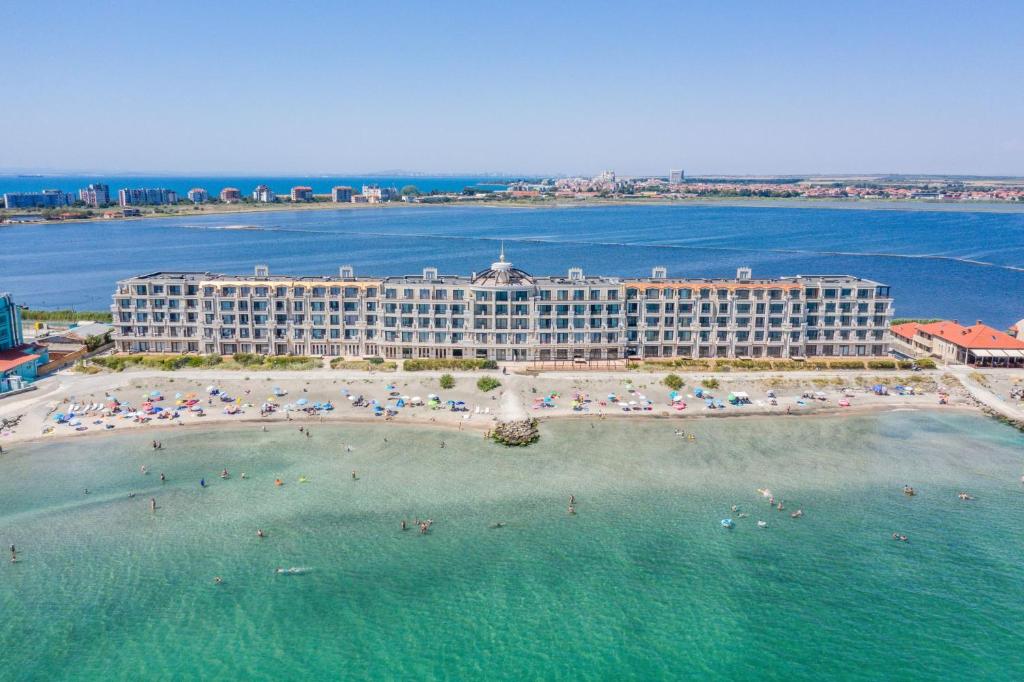 a hotel on a beach with people in the water at Gardenia Beach Palace Aparthotel in Pomorie