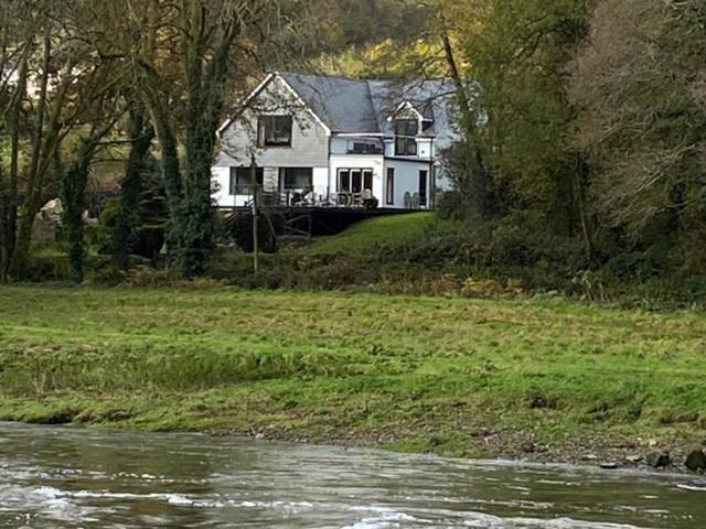 a white house sitting on the side of a river at Riverside Stay in Gunnislake