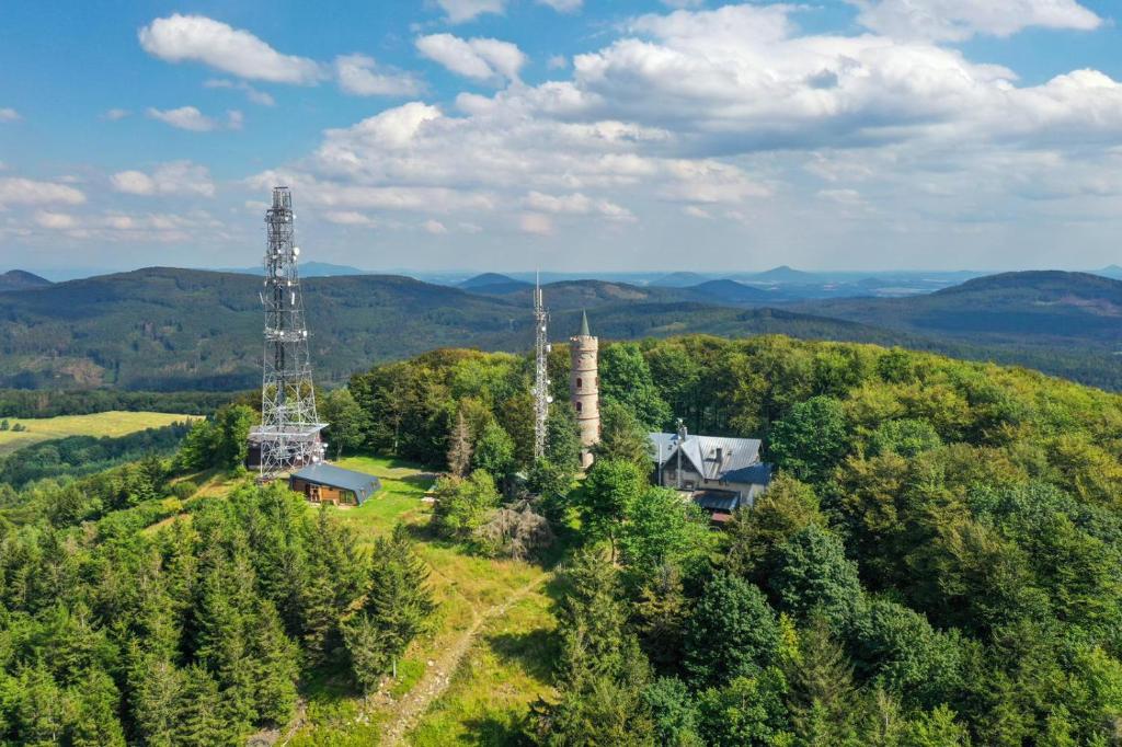 Apartmány Chata Jedlová hora في Jiřetín pod Jedlovou: اطلالة جوية على منزل على تل مع برج