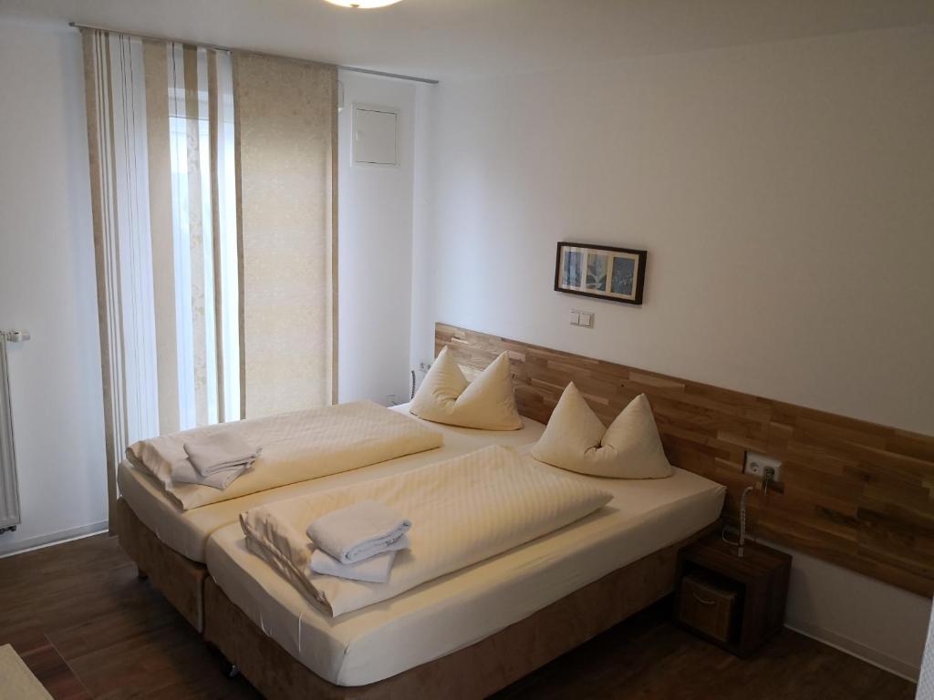 Schlafzimmer mit einem Bett mit weißer Bettwäsche und Kissen in der Unterkunft Gästehaus und Fewo Lamm Garni in Blaubeuren