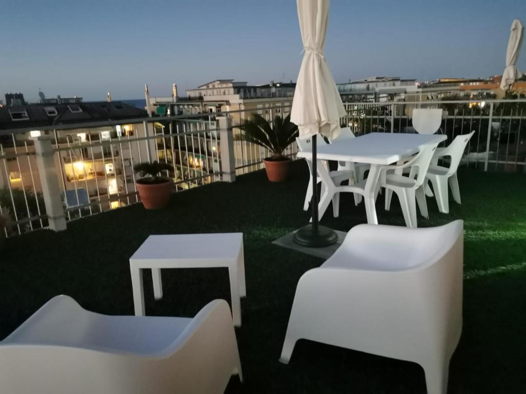 een patio met witte tafels en stoelen op een dak bij LA TERRAZZA in Falconara Marittima