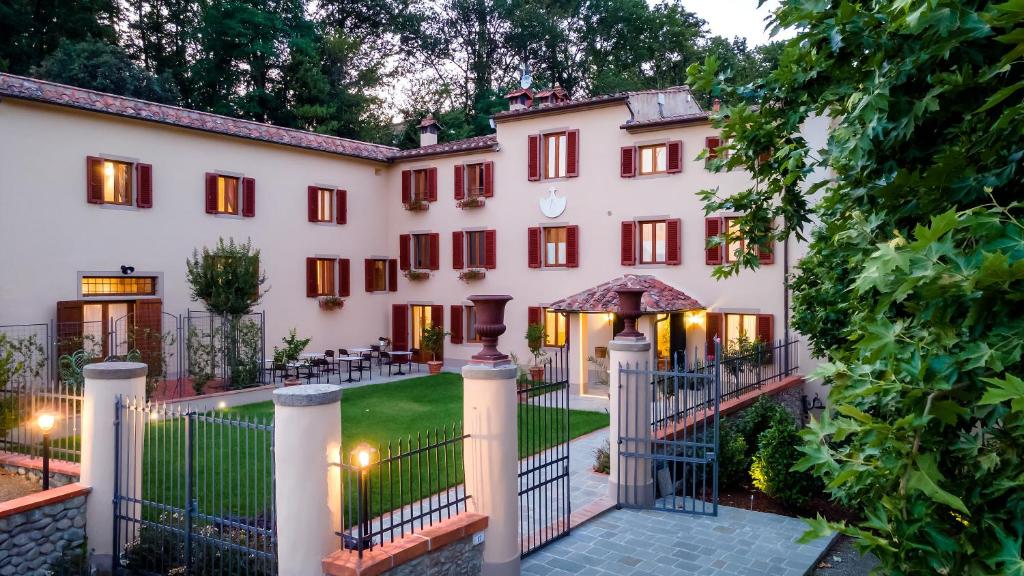 an exterior view of a large white building with a gate at Agriturismo Torreghiotta in Pistoia