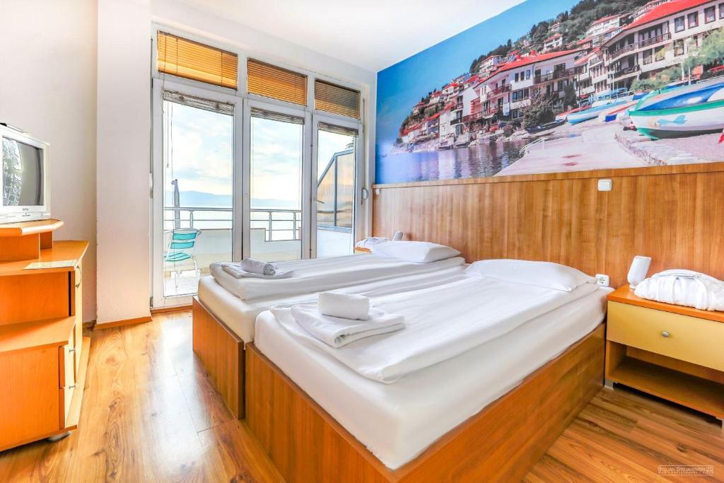 a bedroom with two beds and a painting on the wall at Villa Tino in Ohrid