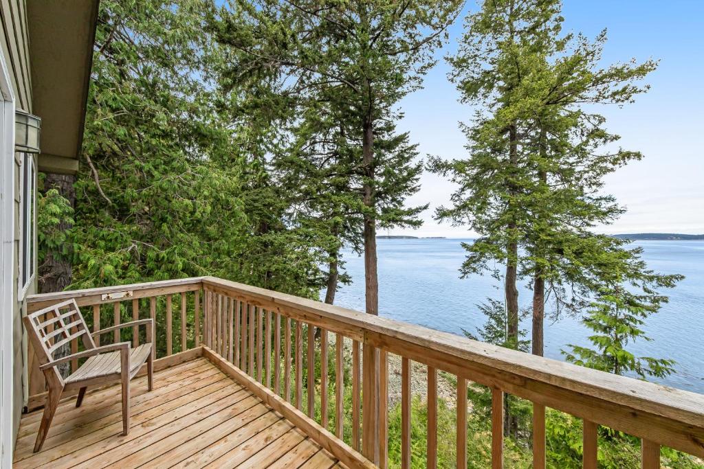 a wooden deck with a chair and the water at Pinecone Cabin in Eastsound