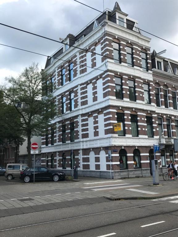 un gran edificio en una calle de la ciudad con coches aparcados delante en hotel Oosterpark, en Ámsterdam